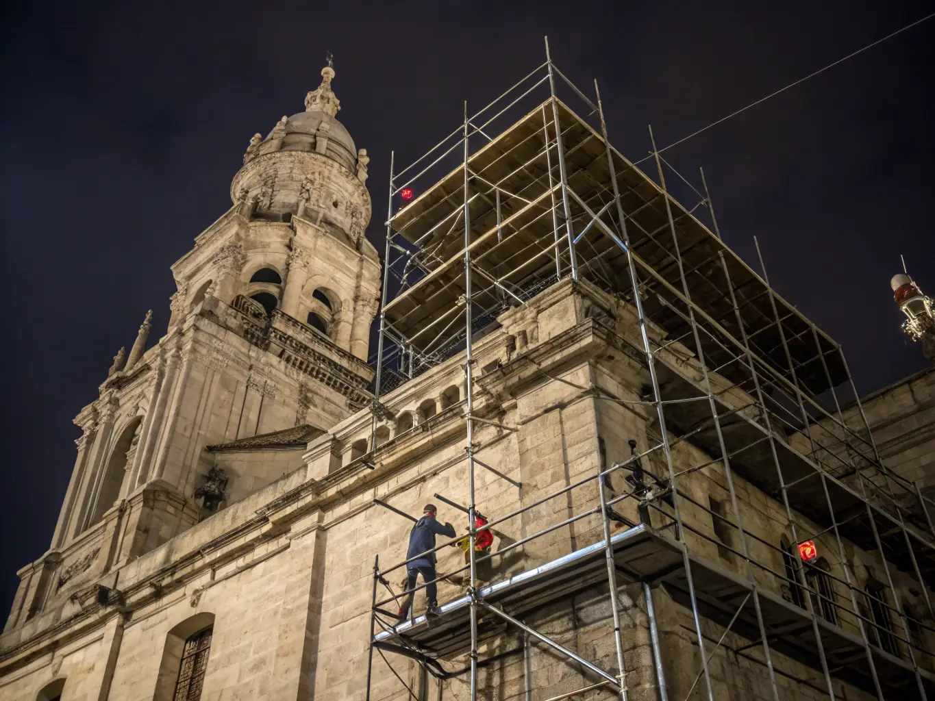 A detailed photograph showcasing the meticulous restoration work being done on the ancient stone facade of the Saint-Martin et Sainte-Anne church, highlighting the skilled craftsmanship involved.