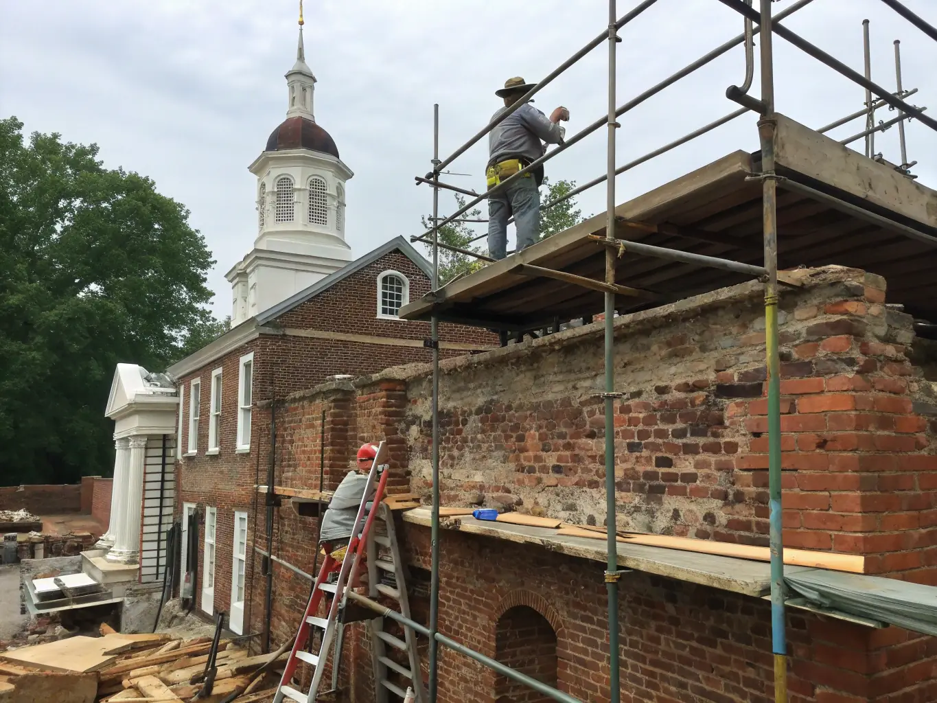 A photograph showing a group of historians and architects examining the structural integrity of the church's facade, highlighting the importance of expert assessment in preservation efforts.