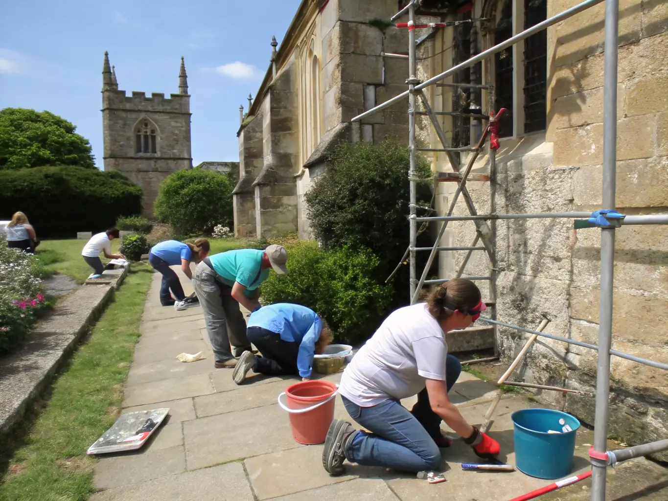 A photograph capturing volunteers meticulously cleaning and restoring a stained glass window at the Saint-Martin et Sainte-Anne church, showcasing the delicate work involved in preserving the church's artistic elements.